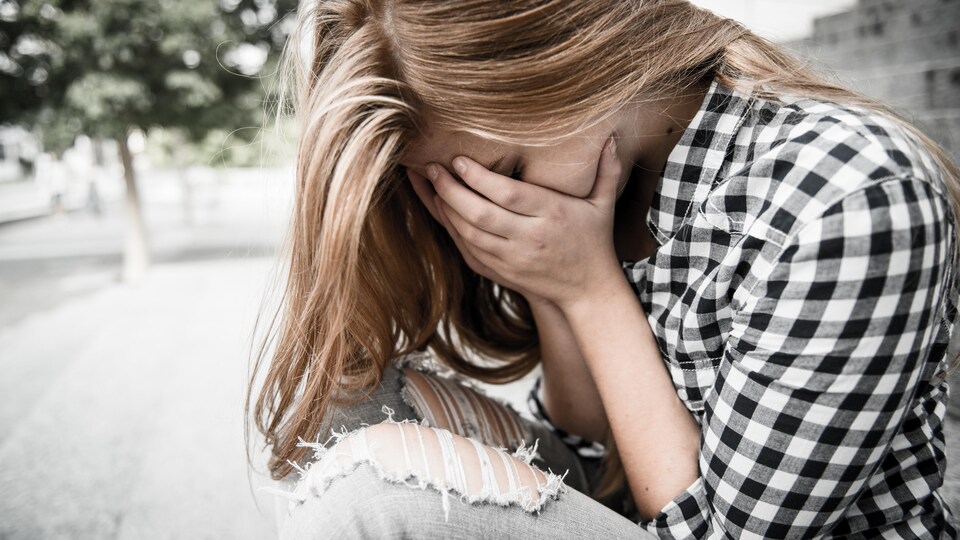 Adolescente avec le visage dans les mains.