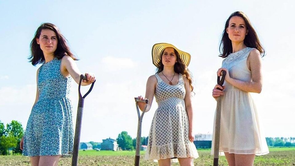 Les soeurs Lefaive dans un champ, des outils à la main