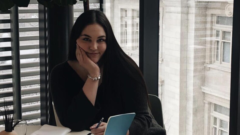 Isabelle Lafond assise devant une grande fenêtre, un stylo à la main