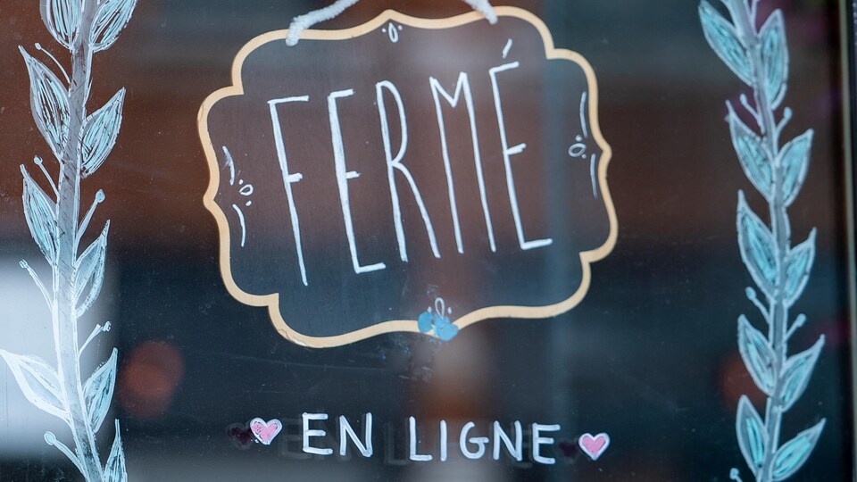 Une affiche sur laquelle ont peut lire « fermé » et « en ligne » dans la porte d'un commerce non identifié.