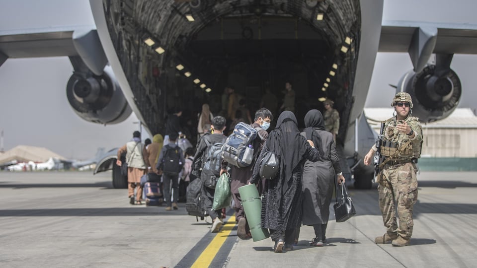 Des réfugiés embarquent par l'arrière d'un avion.