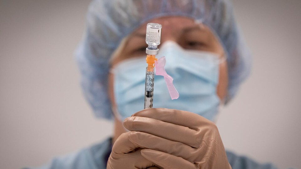 Une infirmière remplit une seringue à partir d'une fiole. 