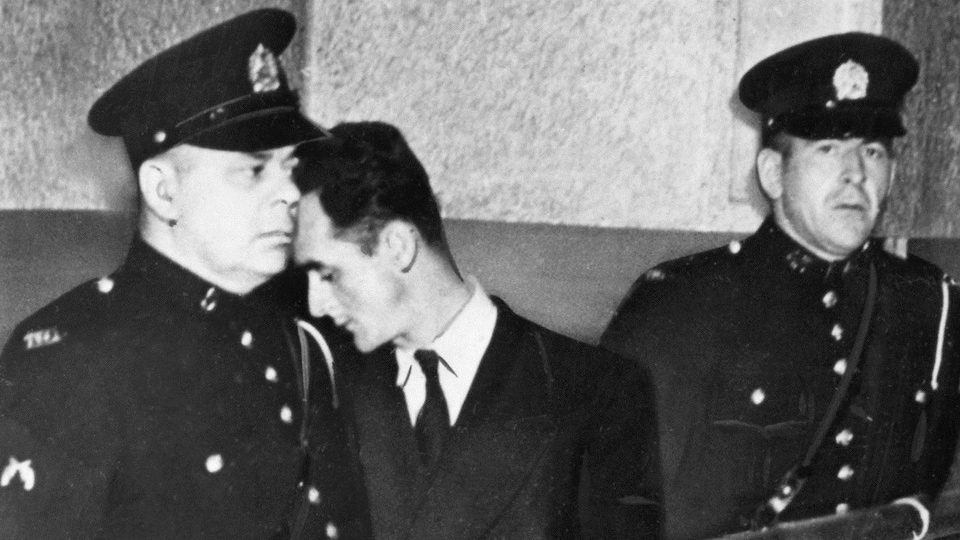 Albert Guay, à la cour entre deux policiers en 1949, pour l'affaire de l'explosion d'un avion au-dessus de Charlevoix, tuant 23 personnes.