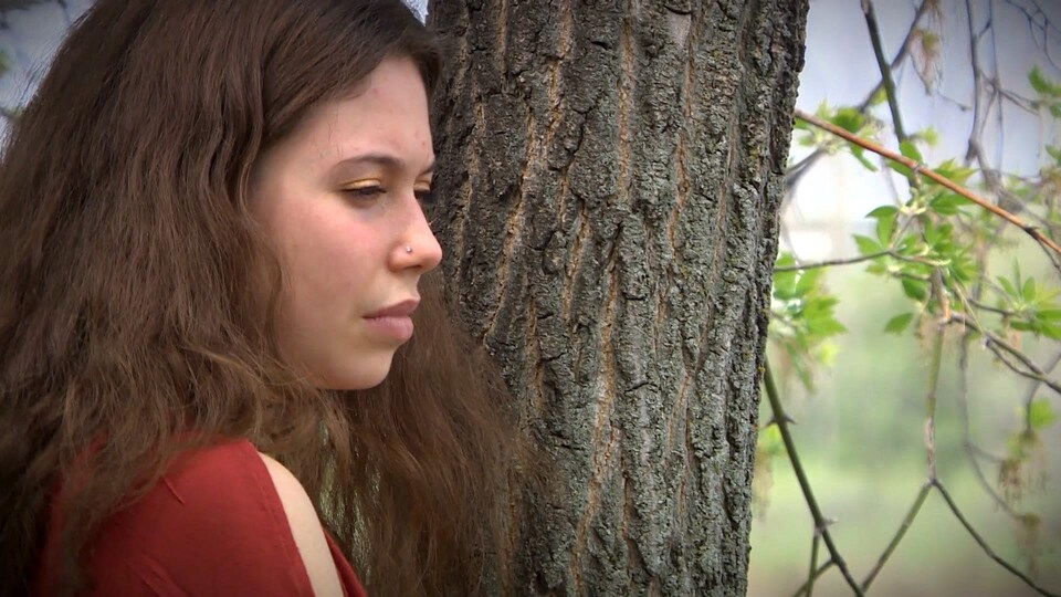 La jeune artiste Amélie Tétrault se tient proche d'un arbre.