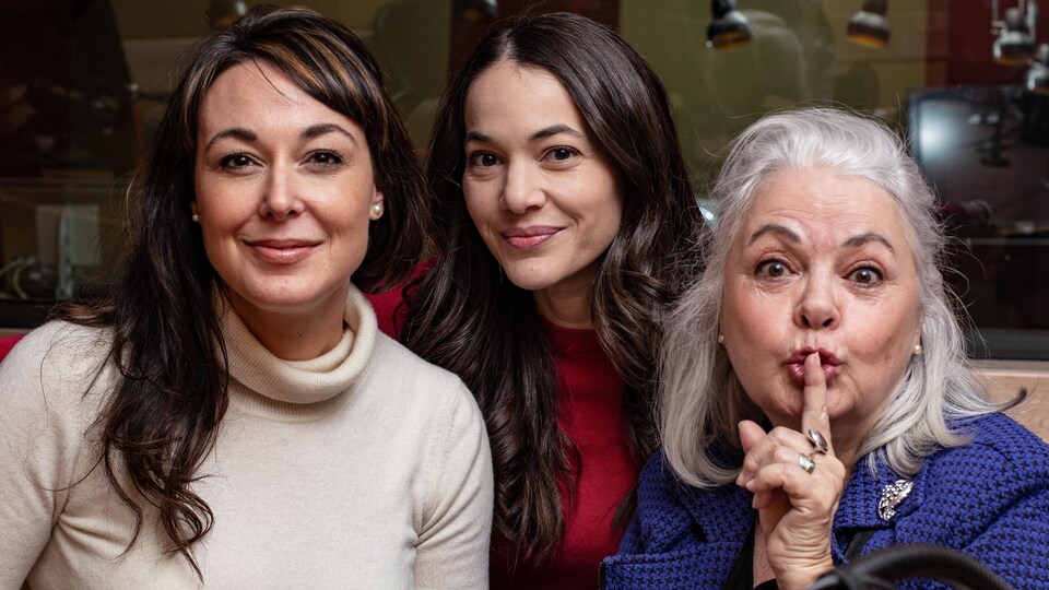 Les trois femmes sourient en posant dans un studio de radio.