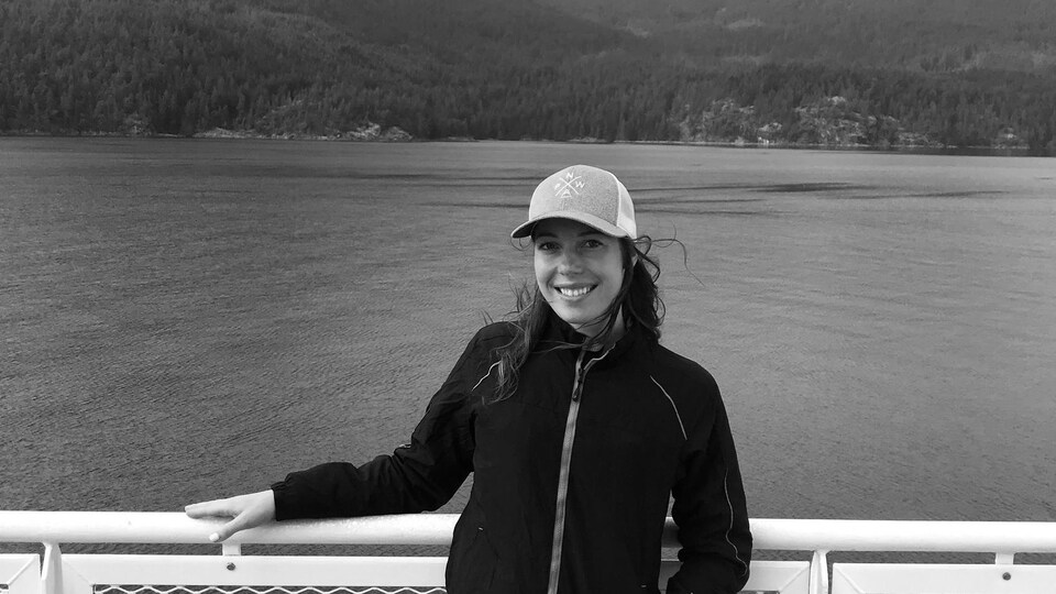 Anaïs Collin sourit sur un traversier de BC Ferries avec les montagnes en arrière-plan.