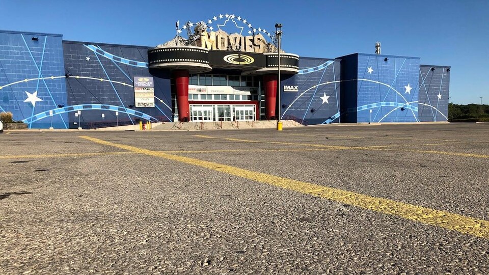 Un grand stationnement vide, avec un cinéma en arrière-plan.