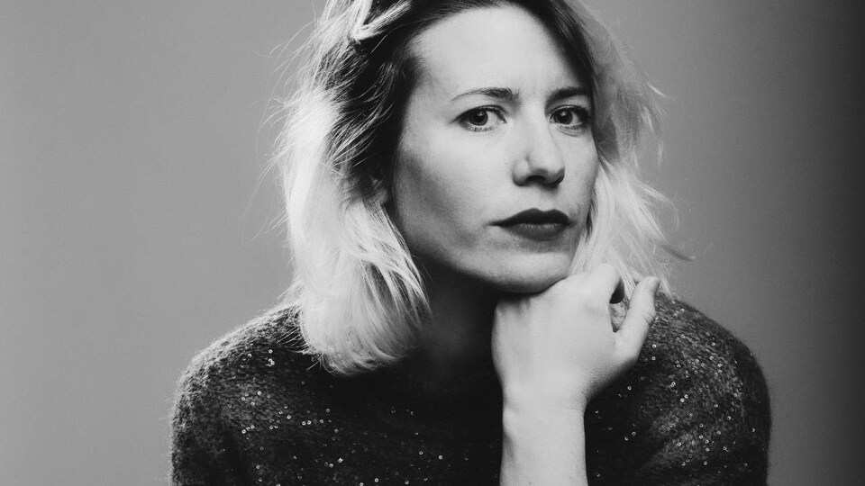 Andréa Saunier pose sur un fond noir et blanc.