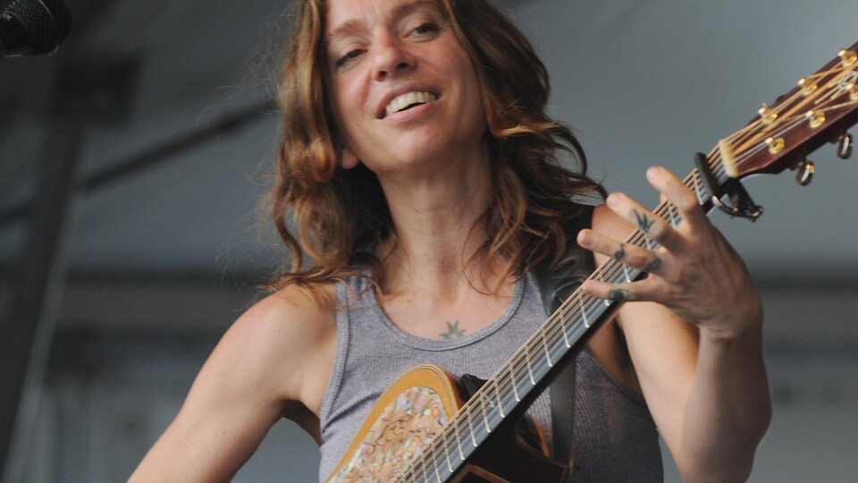 Elle sourit guitare à la main.