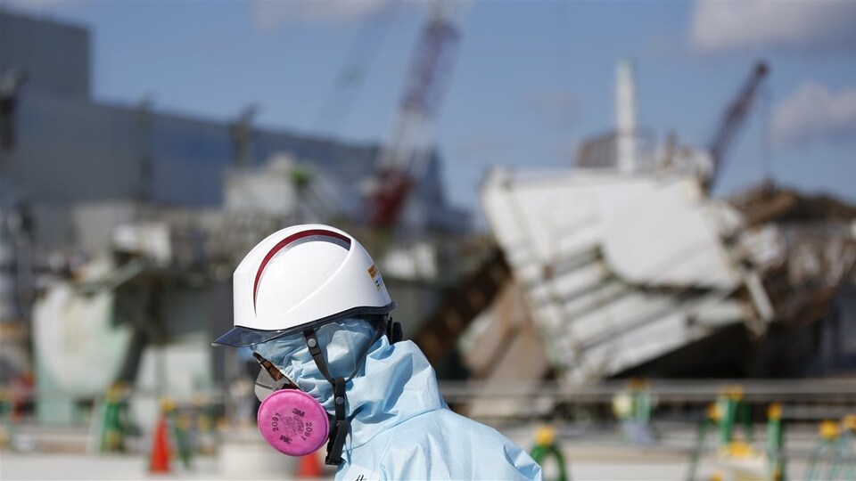 Un employé de la Tokyo Electric Power Company devant les décombres d’un des réacteurs nucléaires à Fukushima