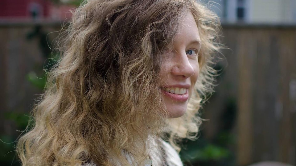 Ann Helga regarde la caméra en souriant, le regard de côté, et porte un pull islandais.