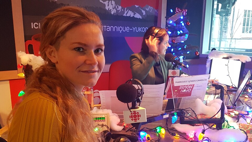 Une femme est dans un studio de radio décoré aux allures du temps des fêtes.