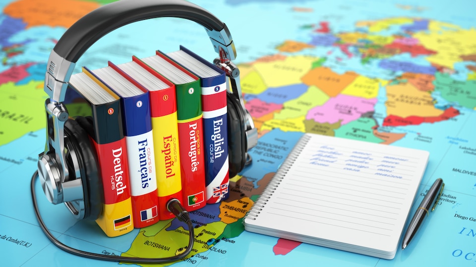 Des dictionnaires et une paire d'écouteurs sur une carte du monde.