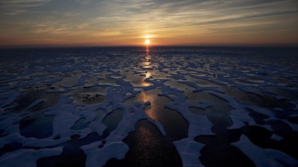 Des morceaux de glace flottent sur l'eau au soleil couchant.
