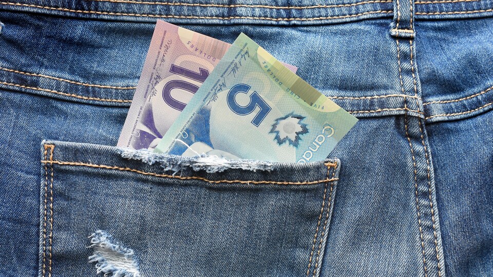 Gros plan sur la poche arrière d'un jeans contenant un billet de 10 $ et de 5 $ canadien. 
