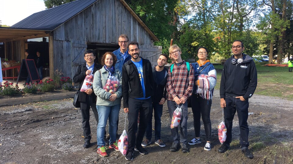 Une groupe d'immigrants tenant des sacs de pommes.