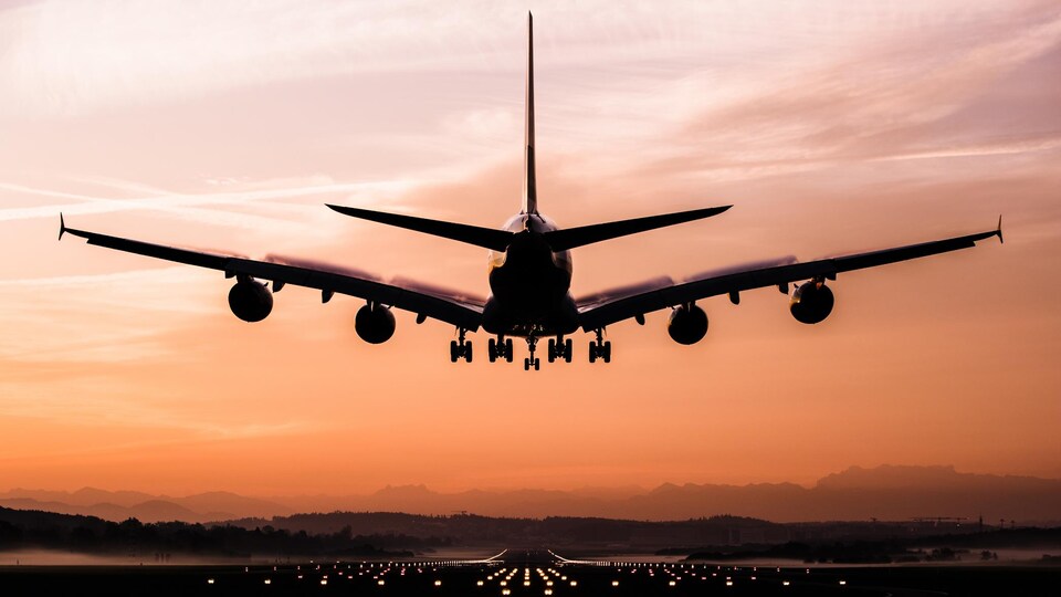 Un avion en train d'atterrir au coucher du soleil.