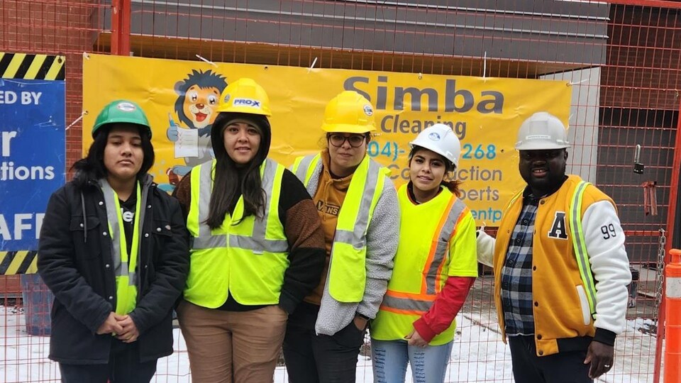 Les employés d'une entreprise de nettoyage debout devant une bannière de l'entreprise Simba Management & Cleaning 