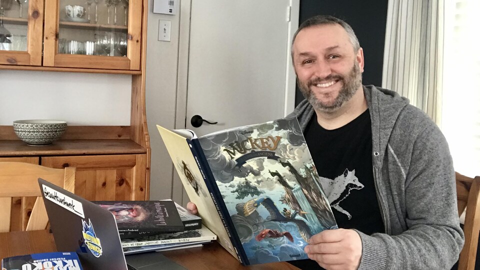 Le chroniqueur BD et enseignant à sa table avec des bandes dessinées.
