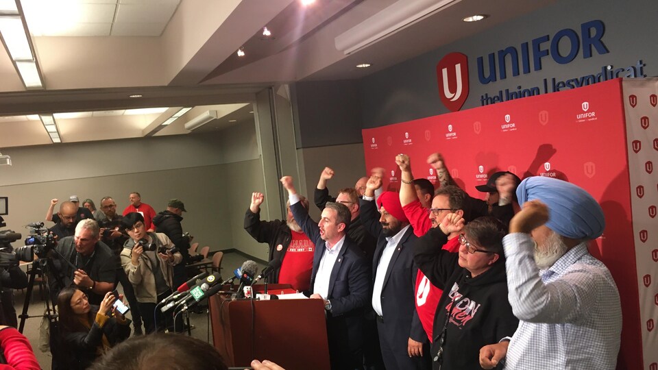 Des membres du syndicat Unifor ont le bras levé lors d'une conférence de presse alors qu'ils annoncent de nouveaux moyens de pression dans la grève des transports à Vancouver