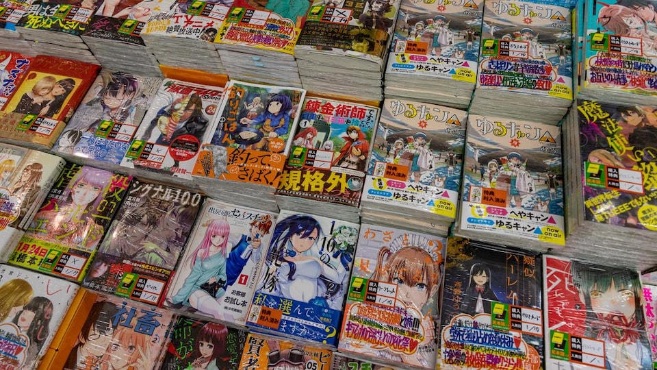 Des dizaines de magazines de mangas sont disposés côte-à-côte dans une boutique.