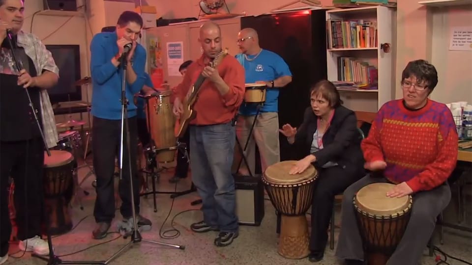 Un groupe de personnes jouant des instruments de musique dans une petite pièce.