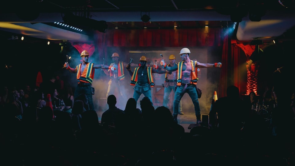 Cinq danseurs sur une scène déguisés en travailleurs de la construction.