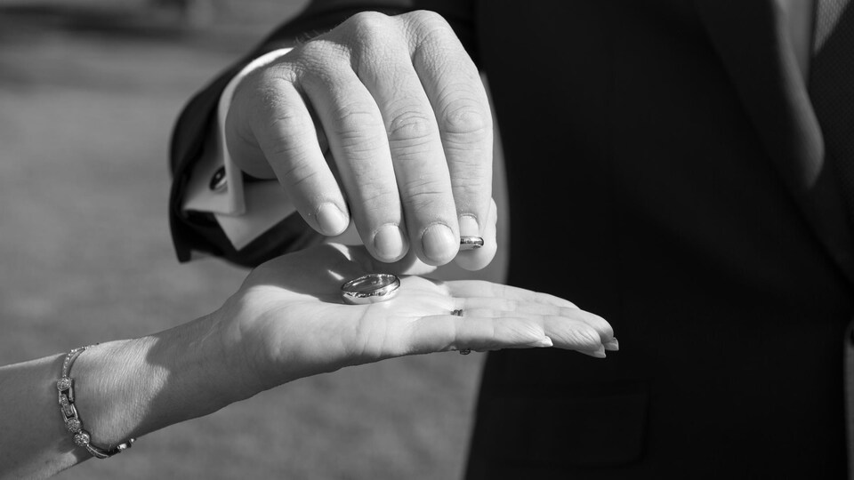 Un célébrant prend un anneau de mariage dans la main d'une mariée.