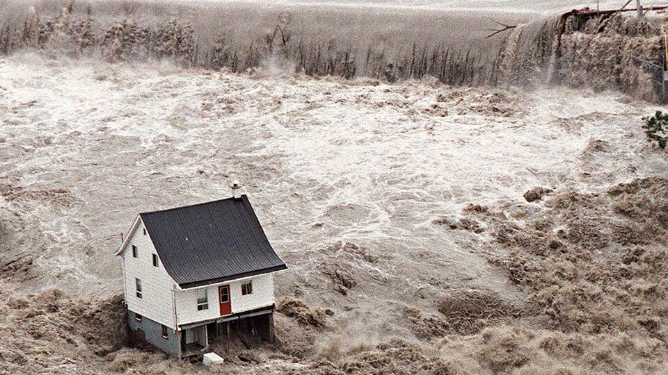 Une maison toujours debout alors que l'eau se déchaîne autour d'elle.