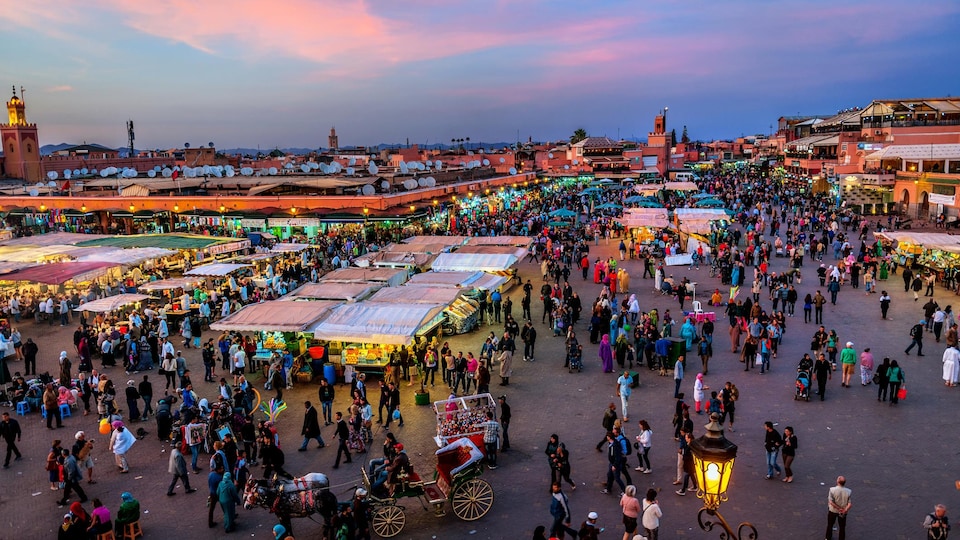 Des gens se promènent autour de place Jemaâ El Fna de Marrakech, au Maroc.