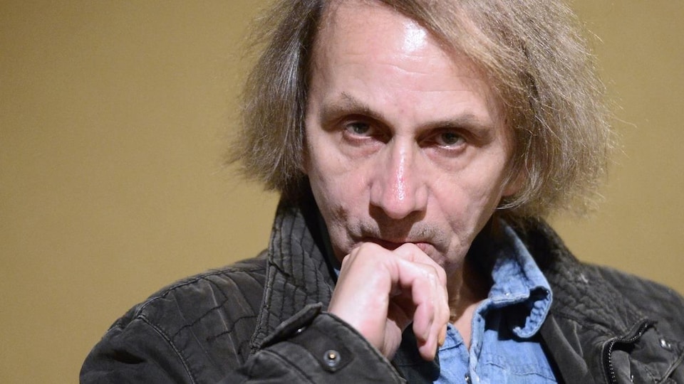 Michel Houellebecq regarde la caméra de manière fixe.