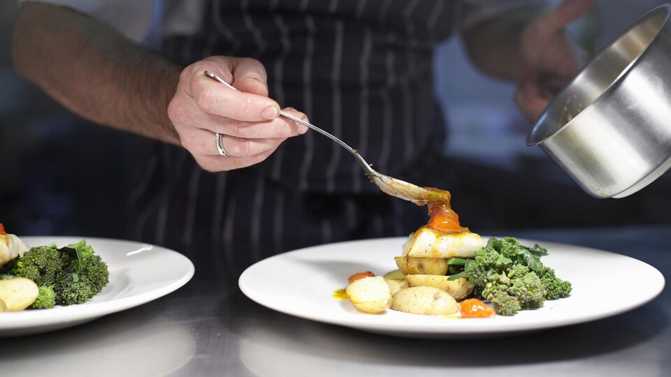 Un cuisinier dispose d'appétissants légumes dans une assiette.