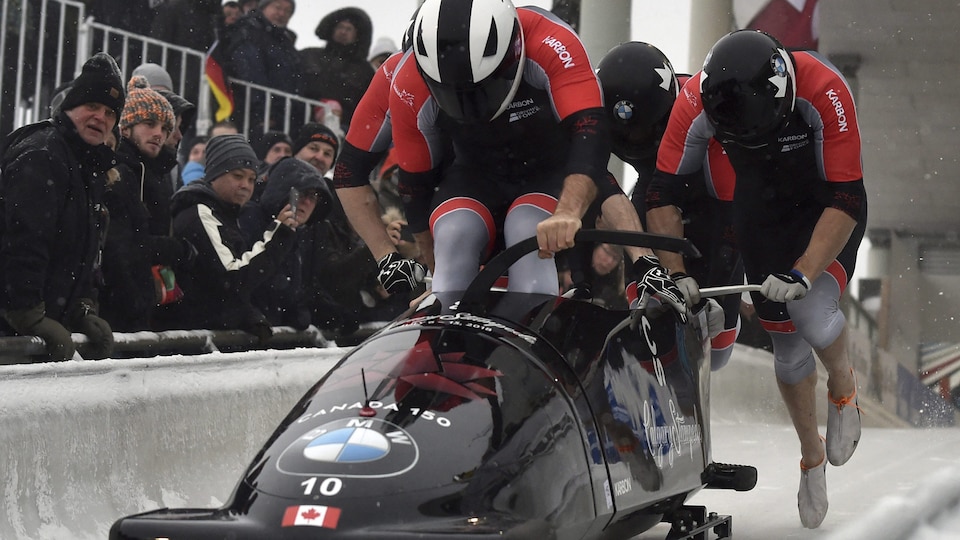 Quatre hommes qui poussent un bobsleigh lors d'une compétition