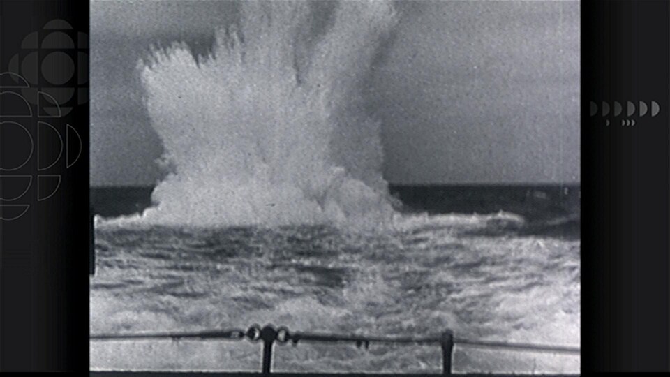 Image en noir et blanc montrant un grand jet d'eau causé par l'explosion d'une bombe dans le fleuve.