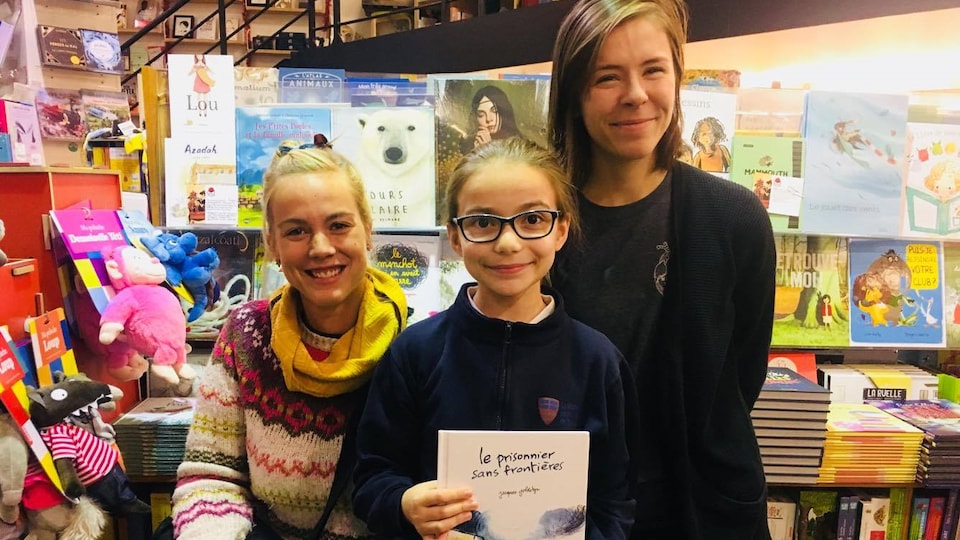 Deux jeunes filles et une libraire, dans la section jeunesse d’une librairie