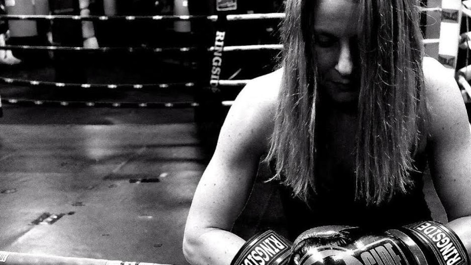 Rachelle Thibodeau, boxeuse et entraîneuse à Pan Am Boxing Club, se tient contre les cordes du ring de la salle de boxe Pan Am Boxing Club, portant ses gants