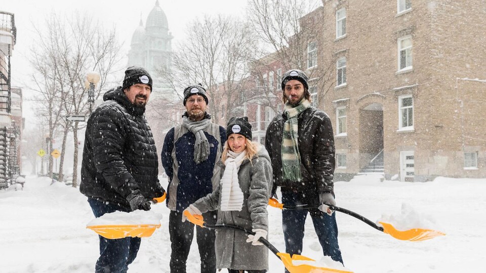 Des jeunes de la Brigade neige prennent la pose avec une pelle.