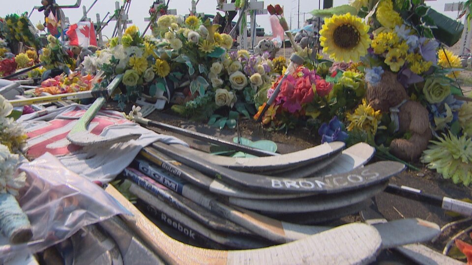 Des fleurs et des bâtons de hockey sont placés sur le lieu de l'accident d'autocar des Broncos de Humboldt en Saskatchewan.