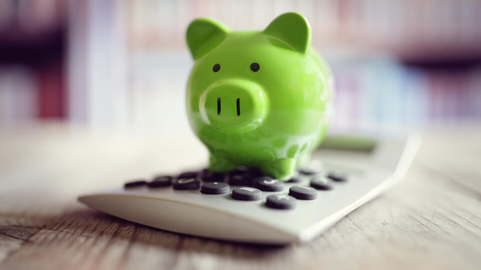 Un cochon vert en porcelaine sur une calculatrice.