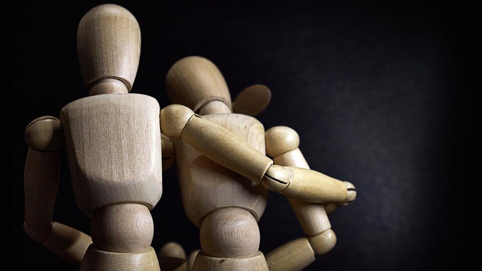 Deux personnages de bois se réconfortent.