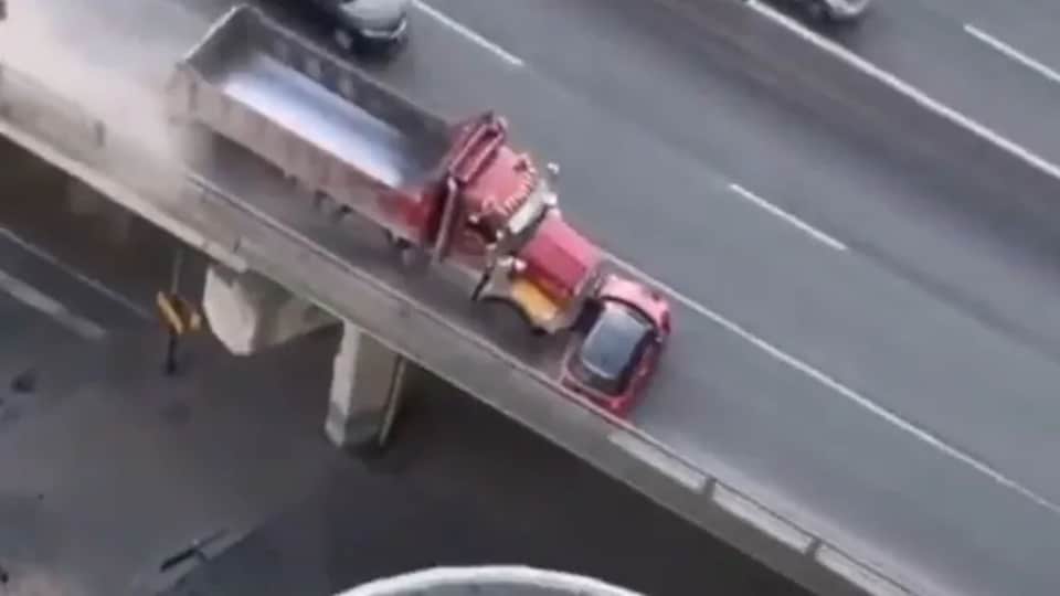 Une image aérienne d'une autoroute où un camion pousse une petite voiture rouge.