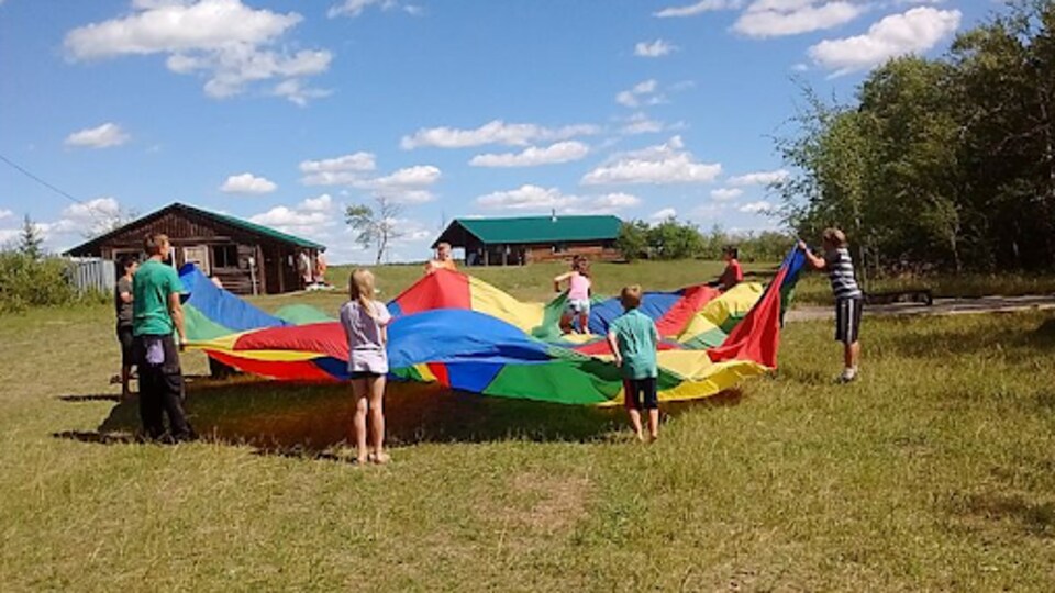 Des enfants jouent avec un parachute coloré à l'extérieur 