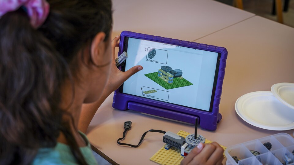 Une jeune fille regarde des instructions sur une tablette.