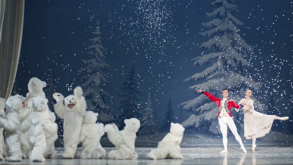 Deux danseurs de ballet dansent sur une scène du Casse-Noisette avec des flocons de neige qui tombent et des petits ours blancs qui s'agitent. 