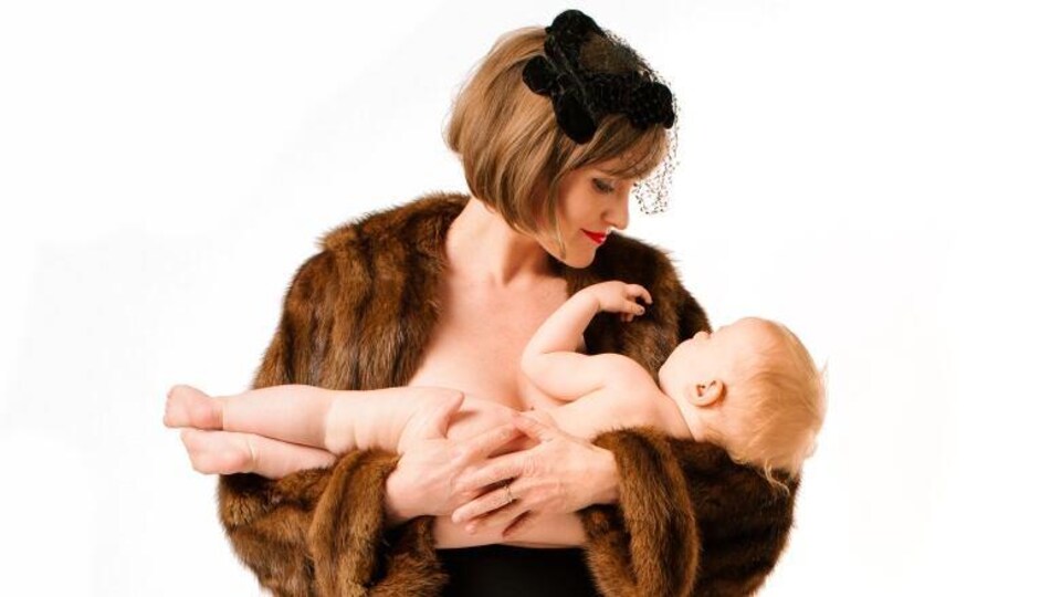 Stéphanie Morin-Robert en manteau de fourrure tient un nourrisson dans ses bras.