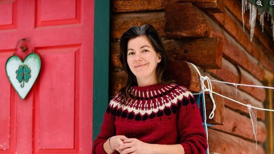 Catherine Bolduc-Gagnon devant une habitation en bois rond.