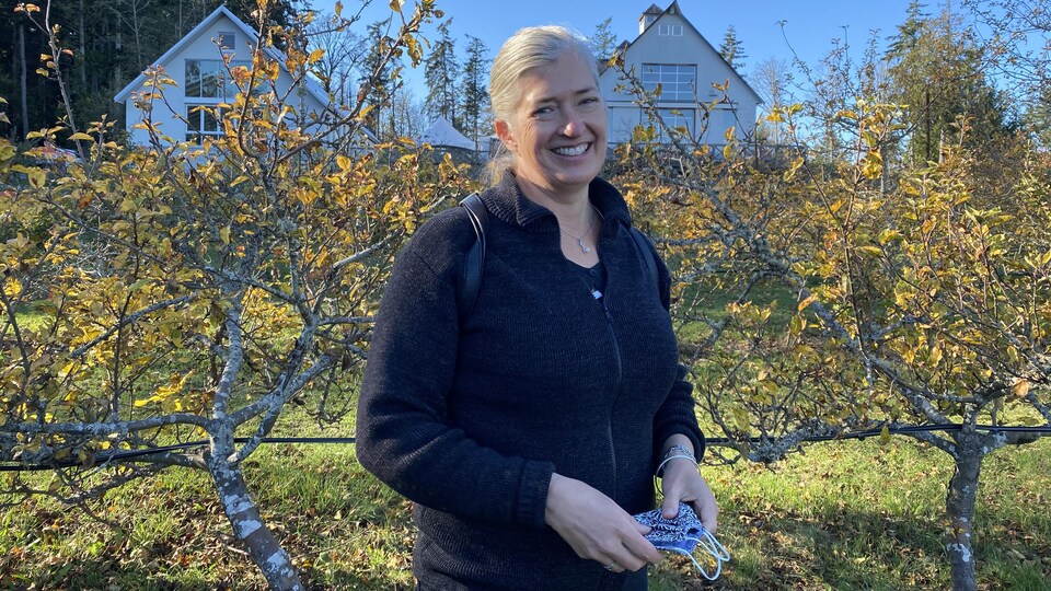 Une femme souriante dans un champ de pommier
