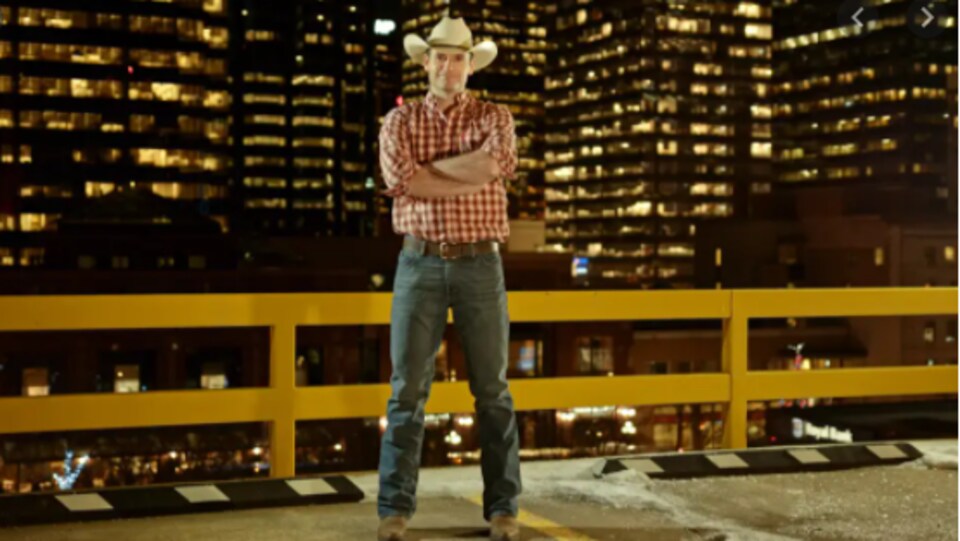 cowboy devant des gratte-ciels la nuit.
