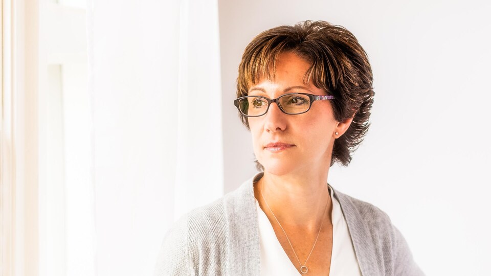 Une femme apaisée près d'une fenêtre.