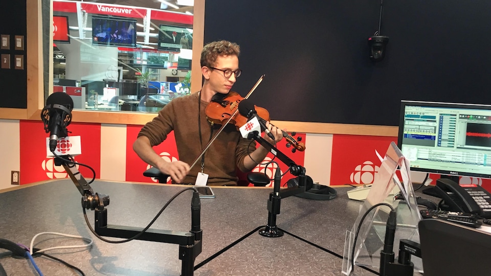 un jeune homme joue du violon dans un studio de radio.